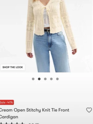Beige stickad kofta med knyt - Superfin beige stickad kofta från New Look med öppet framstycke och knytband vid halsen. Koftan har ett luftigt, virkat mönster och långa ärmar. Perfekt att slänga över en topp för en chill och trendig look.