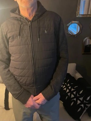 Polo Ralph lauren cardigan - Säljer en grå/ svart cardigan från Polo Ralph med väst material på magen och resten är som en tröja. Köpt på nk förra vintern för cirka 2800kr kvitto finns ej men jag kan skicka bild på tagsen. Skicka 8/10 Inga fel förutom det lilla märket på vänster armbåge då jag knappt använt den pga för liten