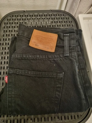 Levi's 501 Premium W28 L32 - Svarta Levi's 501 Premium jeans med klassisk rak passform och fem fickor. Jeansen har gul kontrastsöm och den ikoniska läderpatchen bak i midjan. Materialet är slitstarkt jeans och modellen är straight. Perfekt för dig som gillar tidlös stil.
