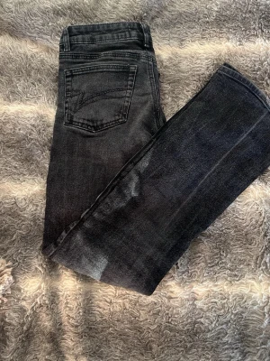 Svarta bootcut jeans från junkyard - Snygga svarta jeans från junkyard med bootcut-snitt och klassisk femficksdesign. Jeansen har en mörk tvätt och är tillverkade i jeansmaterial med stretch. Bakfickan har dekorativ söm som ger extra stilpoäng. Perfekta för dig som gillar en lite vidare passform nertill.