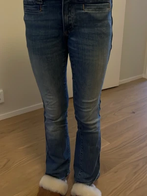 Blå bootcut jeans från hm - Snygga blå jeans från hm  med klassisk bootcut passform. Jeansen har en mörk tvätt med slitningar framtill och bak, fem fickor och dragkedja. Perfekta för dig som gillar en tidlös och cool stil. Materialet är robust jeans i bomull.