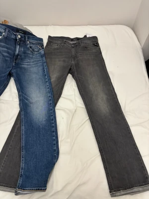 Replay jeans i blått och grått -  600kr styck båda för 1000 kr ,Två par snygga jeans från Replay, ett par i klassisk blå tvätt med ljusa slitningar och ett par i mörkgrå tvätt med lätt blekta detaljer. Båda har raka ben, fem fickor och knappstängning framtill. Perfekta för dig som gillar stilrena och tidlösa jeans. 