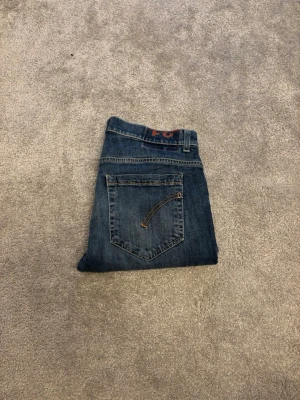 Blå jeans från Dondup, modell George - Säljer ett par blå jeans från Dondup, modell George. Storlek W31 och Längden på jeansen är ungefär 85cm. Klassisk femficksdesign med snygga slitningar och en liten reva på vänster ben. Jeansen har raka ben och är tillverkade i slitstarkt bomullsmaterial. Perfekta för dig som gillar en avslappnad men ändå stilren look. 