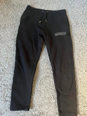 Svarta mjukisbyxor från Hoodrich - Svarta mjukisbyxor från Hoodrich i storlek L. Byxorna har snörning i midjan och fickor på sidorna. Hoodrich-loggan är broderad på vänster lår. Materialet är mjukt och bekvämt, perfekt för chill eller träning.