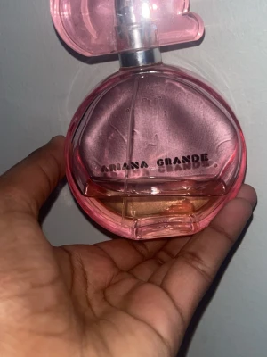 Ariana Grande rosa parfymflaska - Trendig parfym från Ariana Grande i en snygg rosa flaska. Perfekt accessoar för dig som vill sticka ut och addera lite popstjärne-glam till din stil.