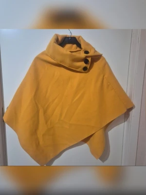 Poncho  - Poncho i senapsgul färg har två små fläckar som syns på bilderna💛🛍