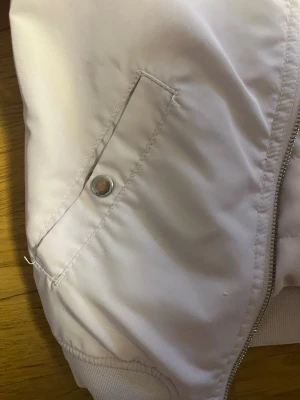 Ljusrosa bomberjacka från H&M - Snygg ljusrosa bomberjacka från H&M med quiltat foder och ribbade muddar. Jackan har dragkedja framtill, två fickor med knapp och klassisk bomberkrage. Perfekt för dig som gillar stilrena och softa jackor.