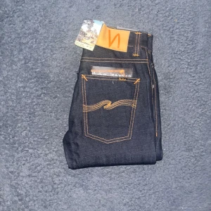 Nudie Jeans Grim Tim  - Helt nya mörkblå Nudie Jeans Grim Tim med slim straight passform.  Perfekt för dig som gillar stilrena och tidlösa jeans. Midja 34cm, längd 109cm.  Ifall det inte finns någon bild i annonsen där jag bär plaggen jag säljer så är det för att jag ej kan ha storleken heller passformen, så kolla måtten för storlek och googla på modellnamnet för passform 😉45