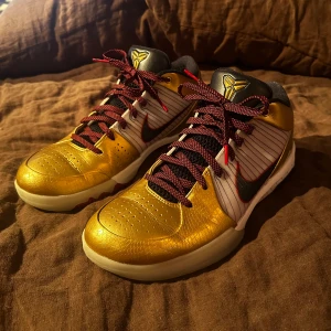 Nike Kobe 4 Protro Gold Medal (2024) - Säljer ett par Nike Kobe IV Protro Gold Medal (2024) som knappt använts. Metallic guld på tå och häl, vita sulor med svarta och röda detaljer samt svart Swoosh. Skorna har röda snören och Kobe-logga på plösen. Någon fundering? Bara att skriva och fråga