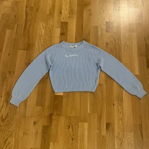 Ljusblå stickad tröja från H&M - Säljer en ljusblå, croppad stickad tröja från H&M med broderad text 'New Hampshire' framtill. Tröjan har långärmade ribbade muddar och en rund halsringning. Perfekt för dig som gillar enkel och chill stil.nästan alldrig anndvänd