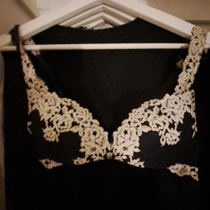 Marin blå bh med blommig spets I 70b  - Säljer en marin blå bh med vacker blommig spets i beige längs axelbanden och över bysten. Toppen har en feminin och elegant design med tydliga kupor och detaljerad spets som ger en lyxig känsla. Perfekt för dig som vill ha något extra till din outfit.