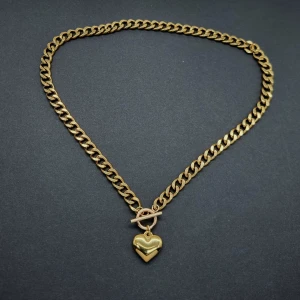 Guldigt halsband med hjärthänge - Snyggt halsband i guldtonad metall med chunky kedja och ett blankt hjärthänge. Material-rostfritt stål. Kedjetjocklek-7cm 