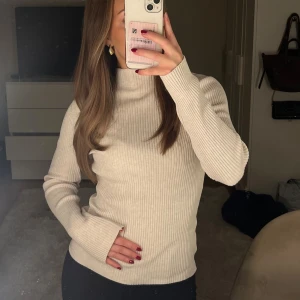 Ribbad topp - Ribbad polotröja i beige med hög hals och långa ärmar. Tröjan är endast använd 2-3 gånger och är i ett mycket bra skick. 💕