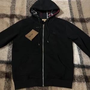 Burberry Hoodie - Säljer en svart Burberry Hoodie i väldigt bra skick (endast testad) den har inga skador, storlek L men passar okså M. Perfekt för vintern för den är varm på insidan och tjock, lapparna finns kvar och kan skickas med vid köp. Vid frågor eller intresse är det bara att skriva ✍️ ✅ Priset kan diskuteras vid bundleköp eller snabbaffär Mvh