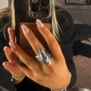 Stor silverring med örnmotiv - Säljer en riktigt cool och chunky ring silverfärgad med detaljerat örnhuvud och fjädrar. Ringen har en unik design som sticker ut och passar dig som gillar statement-smycken. Perfekt för att ge din stil lite edge. Skriv vid funderingar!!