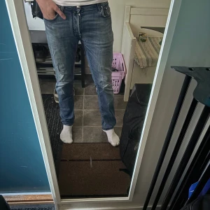 Blå jeans från Jacob Cohën, storlek 32 - Säljer ett par snygga blå jeans från Jacob Cohën i storlek 32. Jeansen har en klassisk femficksdesign, ljus tvätt med slitningar och raka ben. Materialet är mjukt jeans och passformen är normal. Perfekt för dig som gillar stilrena och bekväma jeans. Jeans modell 688 stretch 