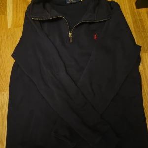 Mörkblå half zip Polo Ralph Lauren - Priset kan diskuteras !!!Mörkblå långärmad tröja från Polo Ralph Lauren med half zip och klassisk röd broderad logga på bröstet. Tröjan har en stilren design och är gjord i mjuk bomull, perfekt för dig som gillar enkel och snygg stil.
