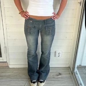 Diesel blå bootcut manchesterbyxor i storlek 32 - Snygga blå manchesterbyxor från Diesel med bootcut passform och låg midja. Byxorna har stora fickor med knappar både fram och bak, samt diskret Diesel-logga på baksidan. Materialet är mjukt och har en cool tvättad look med en gullig ros som knapp!