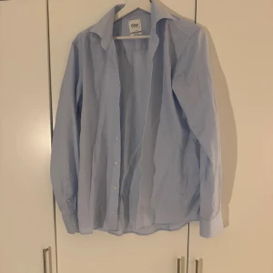 Skjorta från Oscar of Sweden  - Snygg ljusblå skjorta från Oscar of Sweden  i slim fit modell med krage och knappar hela vägen. 