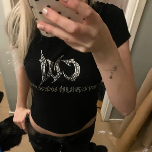 Svart croppad topp med tryck - Säljer en svart croppad topp med korta ärmar och sten detaljer. T-shirten har en slim passform och är stretchig!💕