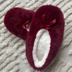Vinröda fluffiga mystofflor - Supermysiga vinröda tofflor med fluffigt pälsmaterial och vit insida. Dekorerade med en söt rosett framtill 🎀Perfekta att bära hemma, oanvända! 🫶🏼