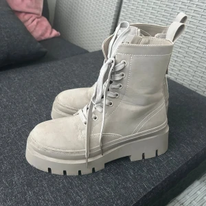 Gråa boots med snörning - Ett par ljusgråa (i lite sammet material nästan så inte glansiga boots) boots. Vattentäta och bra till vintern (dom är vinter skor så varma oxå). Dom är 38 men mer 39. Både med snöre i fram och dragkedja på sidan. Inte mycket använda men prövade några gånger (ute oxå). Lite ”smuts” ifram som man ser på första bilden men kan såklart tvätta bort de innan jag skickar)