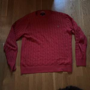 Röd kabelstickad tröja från GANT - Säljer en röd kabelstickad tröja från GANT i storlek M. Tröjan passr bra för det kallare vädret och ger en varm känsla under vintertiden. Tröjan har några år på nacken men har behållit ett hyfsat skick