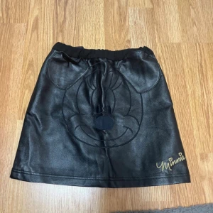 Svart kortkjol med Minnie Mouse  - Svart kortkjol från H&M x Disney, till små barn. Elastisk midja och dragkedja bak. 