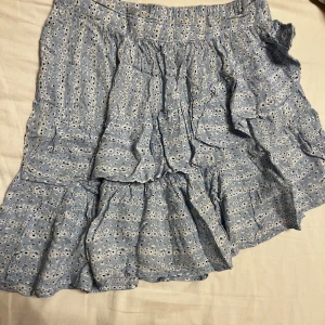 Ljus blå kjol med blommor  - Söt ljus blå asymmetrisk kjol med volanger och vita blommor från Only