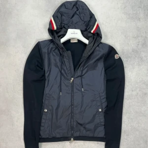 Moncler cardigan tricot jacket - – Condition: 7/10  – Retail price: 10 000 + SEK  Please note that Moncler runs small, we recommend going up one size from your usual size. The model is 185 cm tall and wears L. Bought from a big reseller hear on Plick (är lite solblekt på armarna)