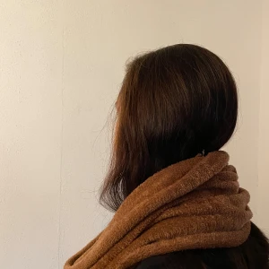 Brun mjuk halsduk i polyamid - En riktigt mysig och fluffig halsduk i varm brun färg. Tillverkad i 100% polyamid vilket gör den supermjuk och lätt att bära. Enkel design utan mönster, perfekt att svepa runt halsen för extra värme under kyliga dagar.