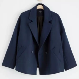 Mörkblå ullkappa från Lindex - Säljer en stilren mörkblå ullkappa från Lindex med bred krage och dubbelknäppning. Jackan har två snedställda fickor framtill och en loose passform som ger en chill vibe. Perfekt för dig som gillar enkel och snygg design.köpt för 1000kr