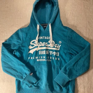 Turkos Superdry hoodie med tryck - | märke: Superdry | plagg: Hoodie | skick: 9/10 | storlek: M | nypris: 1500kr | mitt pris: 349kr | färger: ljusblå/turkos | pris kan diskuteras | hör av dig vid minsta fråga eller fundering // LeClosMatteo