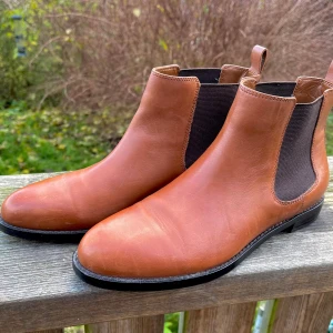 Bruna Chelsea boots från Lauren Ralph Lauren - Eleganta & trendiga Chelsea boots från Lauren Ralph Lauren i skinn Stl:38-39. klassisk rund tå & elastiska paneler på sidorna. En RL-logga i guld på hälen & under sulan sparsamt använda, inga repor. (Swishar helst & ev,går det att mötas upp)