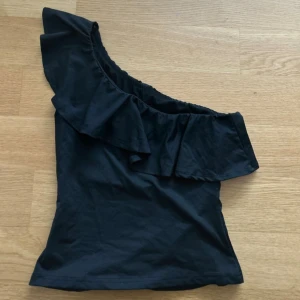 Svart oneshoulder topp med volang - Snygg svart topp med oneshoulder