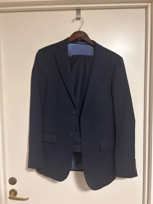Mörkblå kostym Dressmann slim fit - Kostym från Dressmann Använd 1 gång! Mycket bra skick. Kavajen är storlek 46 och Byxorna är W31 L32. Ny pris 2499kr