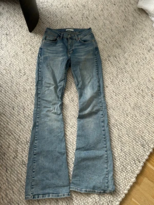 Ljusblå bootcut jeans från Perfect Jeans - Säljer ett par ljusblå jeans från Perfect Jeans i storlek 34. Modellen har låg midja och bootcut-ben, vilket ger en snygg retrovibe. Jeansen är i klassisk denim med fem fickor och dragkedja med knapp framtill.