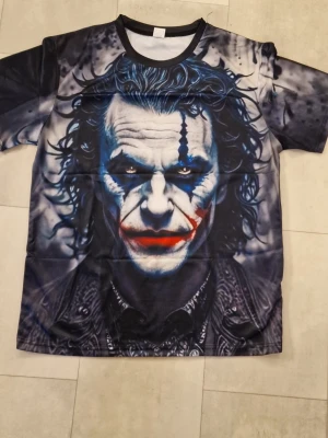 T-shirt Joker - Warner licensierad Joker grafik T-shirt. Bokstavsrund hals, 3D-tryck. Kortärmad. Polyester. T-shirt för män och kvinnor.