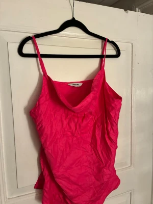 Rosa linnetopp från Kappahl - Säljer en snygg rosa linnetopp från Kappahl med tunna axelband och lätt draperad ringning. Toppen har en härlig, lite glansig finish och är perfekt för varma dagar. Justerbara axelband för bästa passform och luftig känsla.