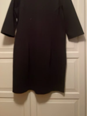 Svart kortklänning från Esprit - En stilren svart klänning från Esprit med enkel design och rund halsringning. Klänningen har lalvlånga ärm och rak passform.Dragkedja bak för enkel påklädning. Storlek xxl (D, UK), bedömer snarare som xl.