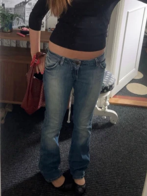 Lågmidjade jeans  - Säljer ett par ljusblå jeans från Wrangler med klassiska W-detaljer på bakfickorna. Modellen har låg midja och bootcut-ben. Storlek w29 och l32 , passar bra på mig som brukar ha S och är 164. Slitna längst ned se bild 