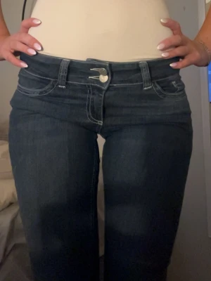 Jeans Nelly - Säljer ett par mörkblå bootcut jeans från Nelly i storlek 36. Jeansen har låg midja, och snygga broderade detaljer på bakfickorna. Andvända endast 1-2 gånger.