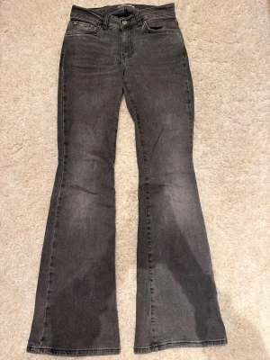 Grå bootcut jeans från Perfect Jeans - Säljer ett par gråa bootcut jeans från Gina tricot Jeans i storlek 32. Jeansen har klassisk femficksdesign, normal passform och är tillverkade i mjukt jeanstyg. Snygg tvättad grå färg och utsvängda ben. 