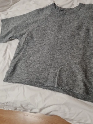 Grå stickad tröja med kort ärm - Mysig grå stickad tröja med korta ärmar och rund hals.