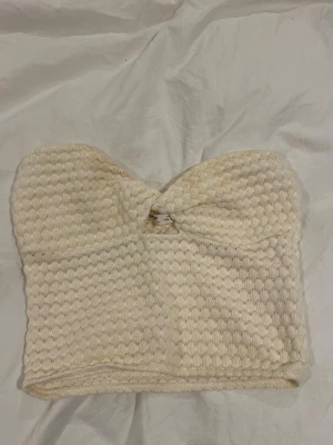 Vit stickad bandeau tubtopp Pull&Bear - Superfin vit stickad bandeau tubtopp från Pull&Bear i storlek S. Toppen har ett snyggt strukturmönster och en twistad detalj framtill. Perfekt till sommaren och knappt använd. Skulle påstå att den är lite mindre i storleken.