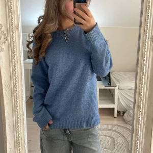 Blå stickad tröja i klassisk modell - Mysig blå stickad tröja med rund hals och ribbade muddar. Perfekt för lager-på-lager och chill dagar. Enkel och stilren design som funkar till det mesta. Snygg till jeans eller kjol.