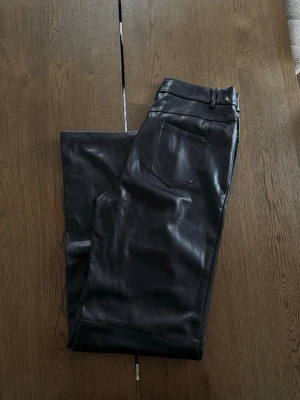 Svarta byxor i skinnimitation - Svarta högmidjade byxor i skinnimitation med raka ben, storlek S. 
