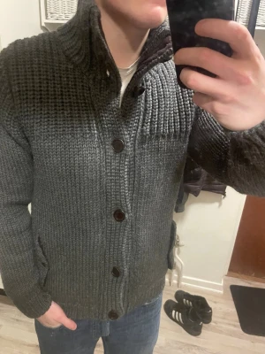 Grå stickad cardigan - Otroligt snygg grå stickad cardigan. Passar perfekt till kallare väder. Modellen är 180cm, 75kg. Priset kan såklart diskuteras!