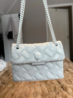 Kurt Geiger väska - Snygg helvit väska från Kurt Geiger. Finns täcken på användning i form av missfärgningar (se bilderna). Jag tycker att detta bara syns på nära håll och inget man tänker på annars. Det är den lilla storleken. 
