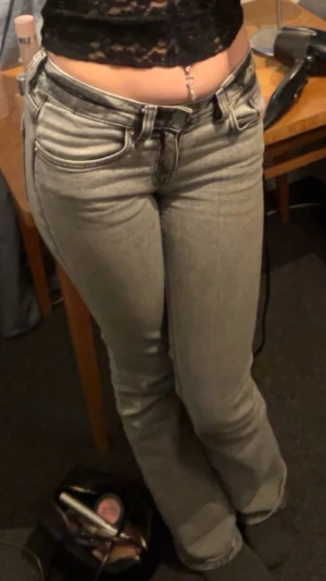 Grå utsvängda jeans med låg midja - Säljer ett par grå jeans med låg midja och utsvängda ben. Jeansen har klassisk femficksdesign och är tillverkade i ett mjukt denimtyg. Perfekta för en avslappnad och trendig look. I storlek Xs men passar även S 